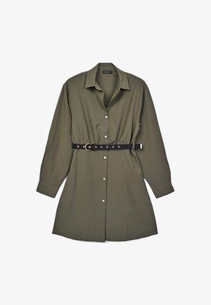 Robe chemise vert olive à manches longues, fermeture à boutons, et une ceinture noire avec des garnitures dorées et plusieurs œillets pour l'ajustement.