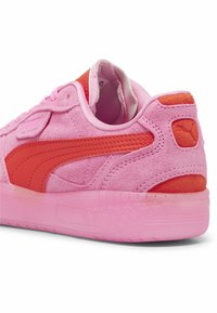 Sneaker in suede rosa con dettagli arancioni, tacco arrotondato e suola in gomma testurizzata. Presenta logo ricamato e colletto imbottito.