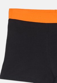 Shorts en coton noir avec une taille élastique orange. Présente une texture lisse et des coutures contrastantes le long des coutures.