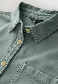 Groene denim overhemd met een spitse kraag, sluiting met twee knopen en een borstzak. Kenmerkt zich door subtiele stiksels en een zachte textuur.