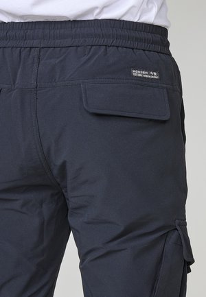 Pantalones cargo en un tono azul marino oscuro con una cinturilla elástica y un bolsillo lateral. La tela tiene una textura suave con un sutil patrón acanalado.