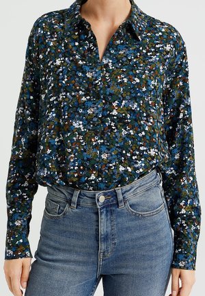 Koszula na guziki w kwiatowy wzór, z ciemnozielonym tłem i niebieskimi, białymi oraz pomarańczowymi akcentami. Długie rękawy i klasyczny kołnierzyk.