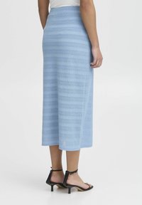Fustă midi țesută de culoare bleu deschis, cu un model texturat în dungi, având un talie ajustată și o siluetă dreaptă. Purtați-o cu sandale negre cu toc.