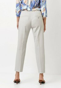 Hellgraue Hose mit geradem Bein, ausgestattet mit zwei Gesäßtaschen und einer glatten Stofftextur. Kombiniert mit braunen Absatzsandalen.