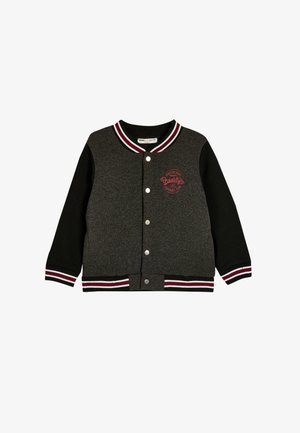 Sort og grå varsityjakke med ribbet krave og manchetter. Har trykknapper og et rødt "Brooklyn" logo på brystet. Blød stofstruktur.