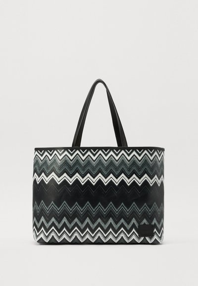Geantă de tip tote cu un model zig-zag alb și negru, realizată dintr-un material plastic neted, cu două mânere negre și o formă rectangulară.