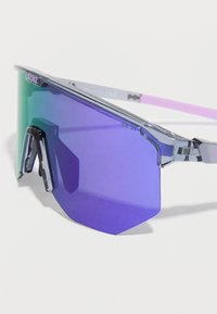 Gafas de sol deportivas con una gran lente iridiscente azul-verde y brazos morados translúcidos sobre un fondo blanco.