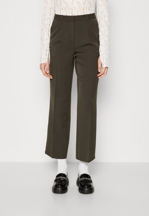 Pantalons taille haute, vert olive, avec un design à jambes droites, comportant des poches latérales et des plis à l'avant. Associés à des mocassins noirs et des chaussettes blanches.