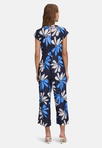 Tuta blu navy con un motivo floreale in blu e bianco, maniche a cappuccio e uno scollo a chiave sul retro. Gamba larga e corta.