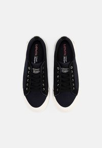 Marina kanvas sneakers med svarta snören, vita gummisulor och Levis-märkning på innersulorna; slät textur, rund tåform.