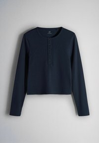 Cămașă henley cu mâneci lungi, bleumarin, cu model ripetat și cinci nasturi în față, așezată plat pe un fundal gri deschis.