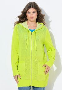 Cappotto cardigan leggero con cappuccio di un brillante verde neon, con zip frontale, ampie tasche e lavorazione a maglia testurizzata. Caratterizzato da maniche lunghe e polsini a coste.