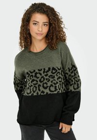 Sweter dzianinowy w oliwkowym zielonym, czarnym i w zwierzęcy wzór. Ma długie rękawy, okrągły dekolt i luźny krój. Teksturowany wzór na klatce piersiowej.