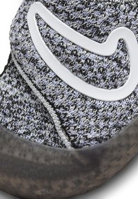 Parte superior de punto en gris y negro con un acento blanco ondulado. Material texturizado con una apariencia suave. Suela de goma con forma redondeada.