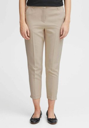 Pantaloni beige su misura con una vestibilità slim, dotati di tasche laterali e una piega lungo la parte anteriore. Realizzati in tessuto liscio, con lunghezza cropped.