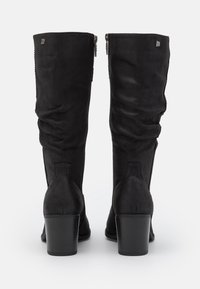 Botas altas de ante negro con un diseño arrugado, punteras redondas y un tacón grueso. Incluye cremalleras en los laterales y una sutil marca en la parte superior.