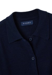 Marineblauwe cardigan van zachte brei-stof, met een klassieke kraag, knoopsluiting en het label "PIOMBO" geborduurd bij de nek.