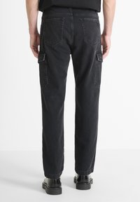 Pantalones cargo negros con un corte relajado, que cuentan con dos bolsillos traseros y un bolsillo lateral. Fabricados con un tejido duradero, de textura suave.