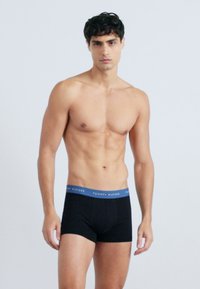 Boxer ajustados negros con una banda elástica azul que presenta el logo "TOMMY HILFIGER", de corte slim, fabricados con un suave tejido elástico.
