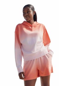 Sudadera con capucha y pantalones cortos en un degradado de rosa claro a coral. Tejido suave, corte relajado y bolsillos frontales en los pantalones cortos.