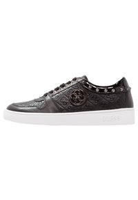 Sneaker in pelle nera con motivo embossé, logo metallico del marchio sul lato, collarino del tallone in vernice con borchie e suola bianca con il testo "GUESS".