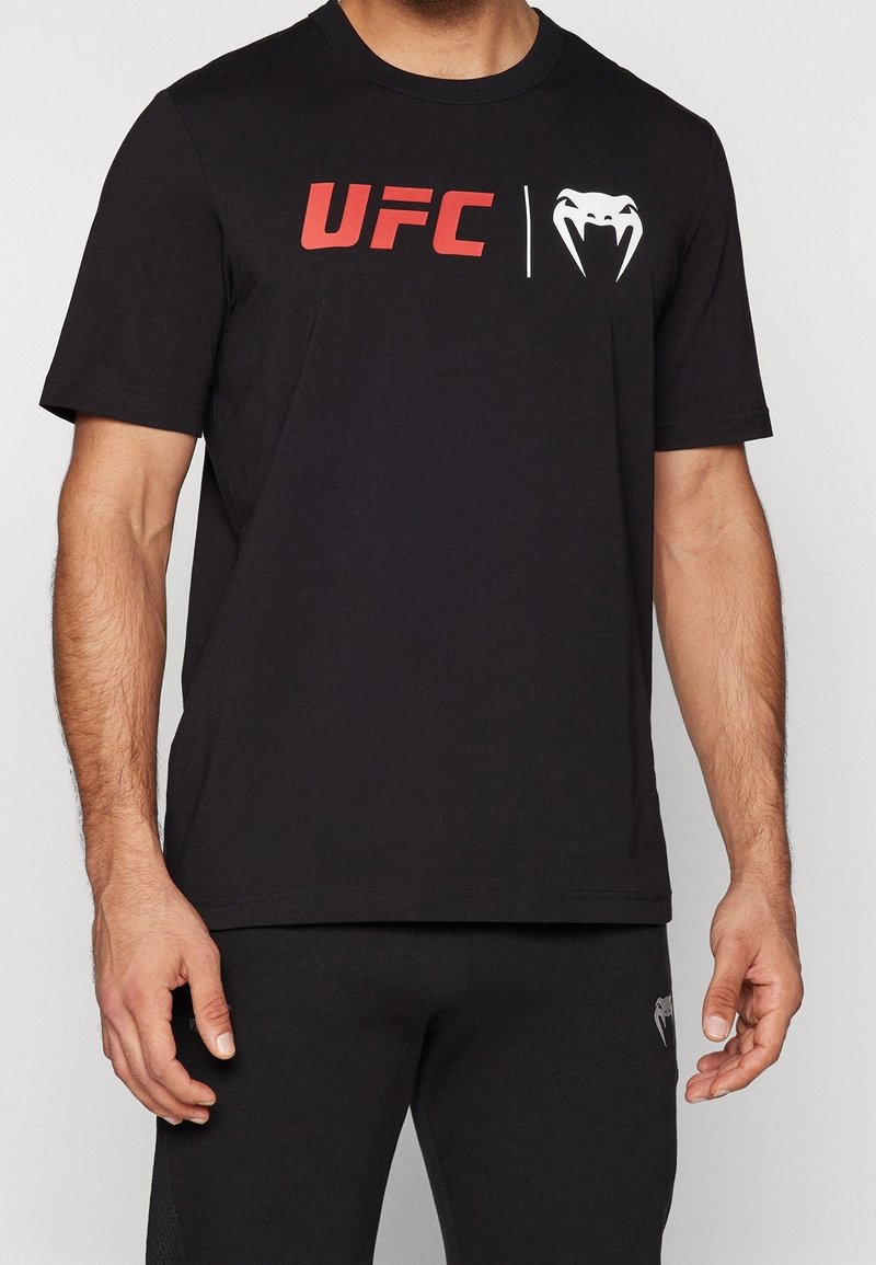 Černé tričko s krátkým rukávem vyrobené z bavlny. Na přední straně se nachází červený nápis "UFC" a bílé logo hada, má kulatý výstřih a klasický střih.