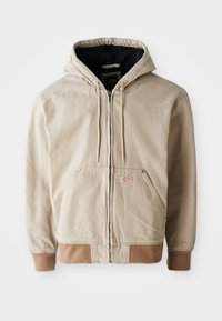 Beige hooded jacket with a zip front, drawstrings, and two front pockets, featuring a contrasting brown ribbed hem and cuffs.