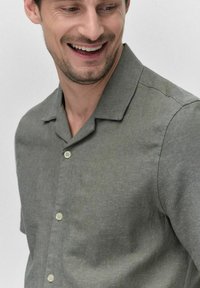 Korte mouwen knoopshirt van lichtgroene textuurstof; met een kraag en drie bleke knopen.