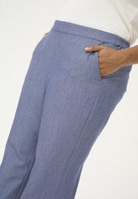 Pantaloni a gamba larga in tessuto intrecciato azzurro chiaro con vita elastica e tasche laterali. Texture liscia con una vestibilità elegante.