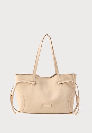 Borsa tote in camoscio beige con lacci laterali regolabili, spallacci piatti e base rettangolare. Presenta un piccolo dettaglio con logo in metallo.