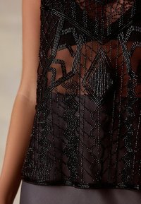 Must mustriline aasakate mustrite geomaatrilisi mustrid, kontrasteerivad tekstuurid ja poolläbipaistev kangas. Omab lainelisi ja sirgeid helmeste mustreid.