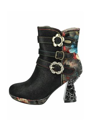 Black faux suede ankle boot with decorative straps and floral-patterned heel. Features metal accents and a textured, embellished heel.