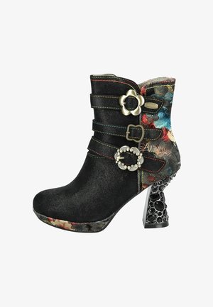 Stivaletto in ecopelle scamosciata nera con cinturini decorativi e tacco con motivo floreale. Presenta dettagli metallici e un tacco testurizzato e impreziosito.