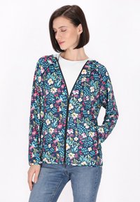 Giacca con zip floreale su sfondo blu scuro, caratterizzata da vivaci motivi floreali, cappuccio e una texture di tessuto morbido.