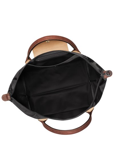 Schwarze Stofftasche mit braunen strukturierten Ledergriffen, braunem Lederelement und ungefüttertem Innenraum mit Reißverschluss.