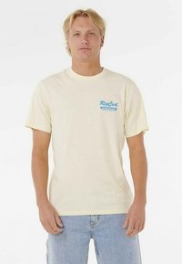 Cream cotton t-shirt with short sleeves, featuring a blue Rip Curl logo on the left chest. The fabric appears soft and smooth.