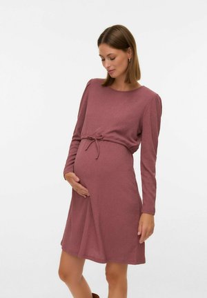 Zwangerschapsjurk in stofkleur dusty rose, gemaakt van een gestructureerde stof. Heeft lange mouwen, een ronde halslijn en een aansluitende tailleband boven een ronde buik.