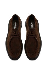 Scarpe in suede marrone con punte rotonde, dettagli cuciti e suole in gomma scure. Presentano lacci in pelle per la regolazione. Design semplice.