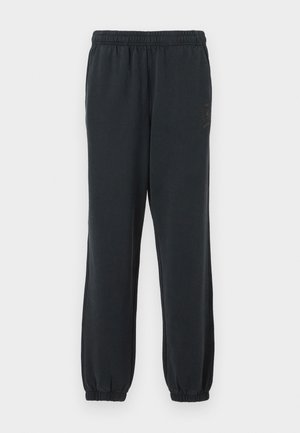 Black cotton sweatpants with an elastic waistband and cuffs. Features a subtle logo detail on the left thigh, smooth texture throughout.