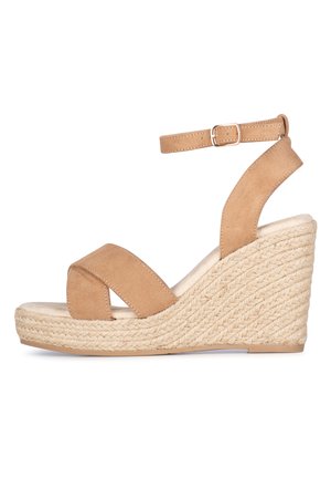 Tanfarbene Wildledersandalette mit zwei gekreuzten Riemen und einem verstellbaren Knöchelriemen. Mit einer geflochtenen Jute-Umrandung am Plateauabsatz.