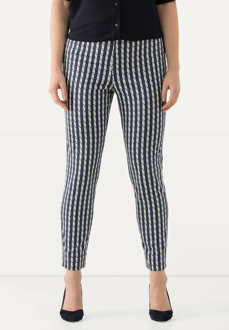 Marinblå och krämfärgad mönstrade byxor med vertikala ränder, slim fit, slät textur och avkortad ankellängd, i kombination med mörka klackar.