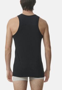 Schwarzes ärmelloses Shirt mit Rundhalsausschnitt, glattem Stoff und slim fit, das das Design des Rückens und der Schultern zeigt.