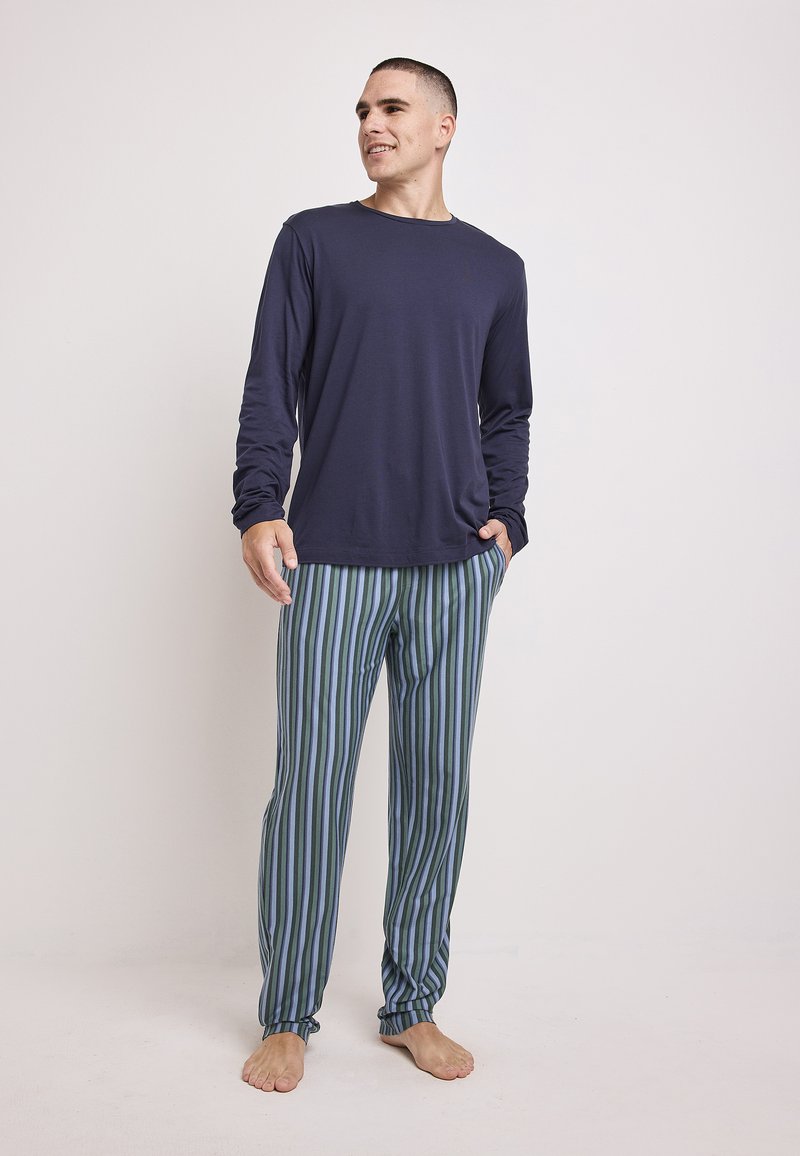 Camisa de manga larga de color marino combinada con pantalones de pijama a rayas verdes y azules. Tejido suave, corte relajado y puños en los tobillos de los pantalones.