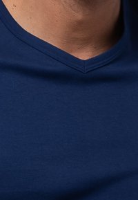 Marineblauwe V-hals t-shirt gemaakt van gladde katoenstof, met een aansluitend ontwerp en subtiele textuur over het oppervlak.