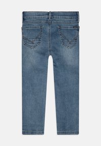 Jeans de mezclilla en un lavado azul medio con un ajuste slim, que cuentan con dos bolsillos traseros, costuras decorativas y un corte recto.