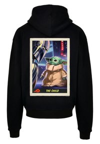 Černá mikina s kapucí, na které je grafika zelené postavy v béžovém plášti, vedle ní je postava v brnění vlevo. Doplňuje ji rámeček a text.