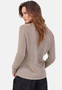 Pull en tricot beige avec une coupe décontractée, poignets côtelés et motif au dos. Texture douce avec un motif subtil et manches mi-longues.