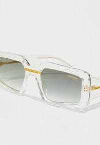 Ochelari de soare supradimensionați, pătrați, cu lentile gradient, accente din metal auriu și rame transparente. Prezintă eticheta de protecție UV pe lentilă.