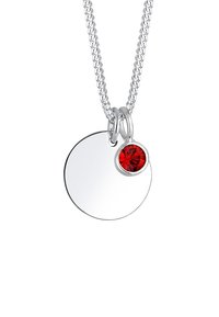 Collier en argent avec un pendentif circulaire à surface polie et une petite pierre rouge en accent. La chaîne est texturée et de épaisseur moyenne.