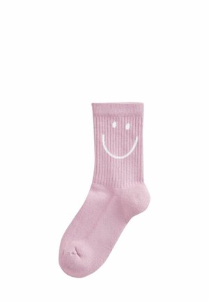 Calcetín de color rosa claro con textura acanalada que presenta un diseño de cara sonriente blanca en el tobillo. Textura suave, longitud estándar de caña, construcción sin costuras en la punta.